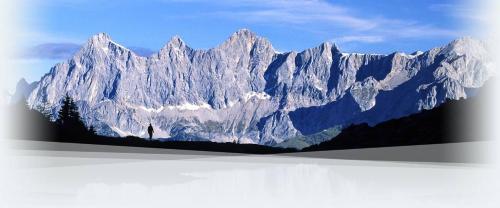 a large snow covered mountain with a person in front of it at Landhaus Ramsau in Ramsau am Dachstein
