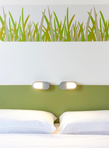 a bedroom with two white beds and a green wall at ibis budget Leicester in Leicester