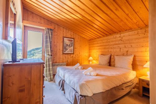 una camera da letto con un letto in una cabina di legno di Mont Vallon #35 a Méribel