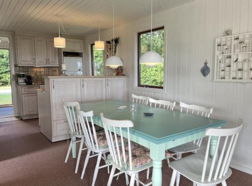 a kitchen with a blue table and white chairs at Holiday Home By Limfjord With Historic Charm in Farsø