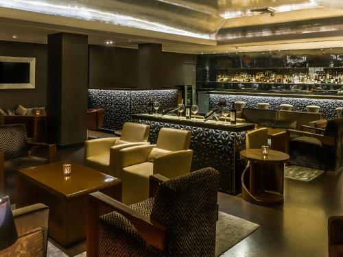 a restaurant with a bar with chairs and tables at The Claridges New Delhi in New Delhi