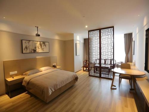 a bedroom with a bed and a desk and a table at GreenTree Inn Anhui Hefei South Railway Station Damo Sqaure Business Hotel in Hefei