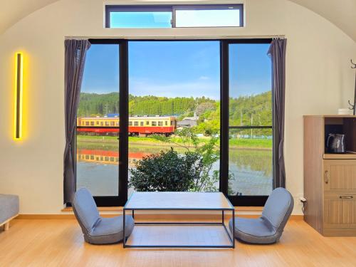 a living room with a table and chairs and a train at 湊乃里 小湊鉄道沿線で自然とレトロな雰囲気を楽しむ貸切古民家 市原 高滝 in Ichihara