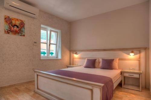 ein Schlafzimmer mit einem großen Bett mit lila Kissen in der Unterkunft Piazza Apartments 1 in Petrovac na Moru