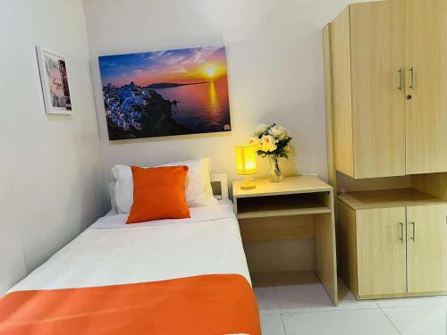 a small bedroom with a bed with an orange pillow at OYO 1158 Kegama Residences 2 in Cavite