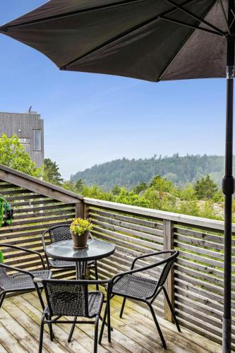 a table and chairs on a deck with an umbrella at Cabin With 360-Degree Views In Risør in Søndeled