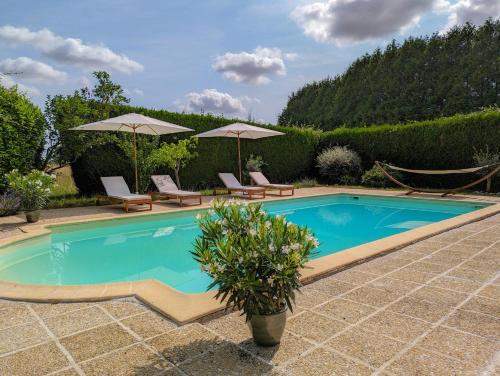 una piscina con dos sillas y sombrillas en Charming House Near Loire Valley Castles, en Josnes