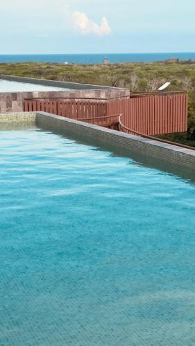 a large pool of blue water next to a fence at Jungle Guardian - Rooftop Pool & Beach Club in Zona Hotelera Tulum in Tulum