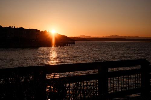 a sunset over a body of water with a fence at Bos Cozy Victorian Top Floor Duplex Unit with Puget Sound views in Tacoma