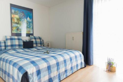 a bedroom with a bed with a blue and white checkered blanket at ausZEIT - Ihr Sibyllenbad Gästehaus in Neualbenreuth