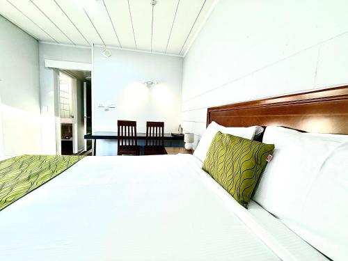 a bedroom with a bed with white sheets and green pillows at Admirals Motor Inn in Nelson