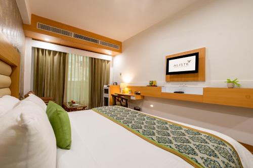 a hotel room with a bed and a flat screen tv at Aliste Millennium Huda City Centre in Gurgaon