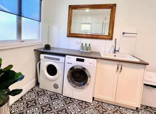 une salle de bain avec une machine à laver et un lavabo dans l'établissement Artist's Cottage - Cosy Home in Quiet Leafy Street, à Toowoomba