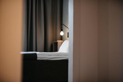 a room with a bed with a lamp and curtains at Hotell & Bistro Rödesund in Karlsborg