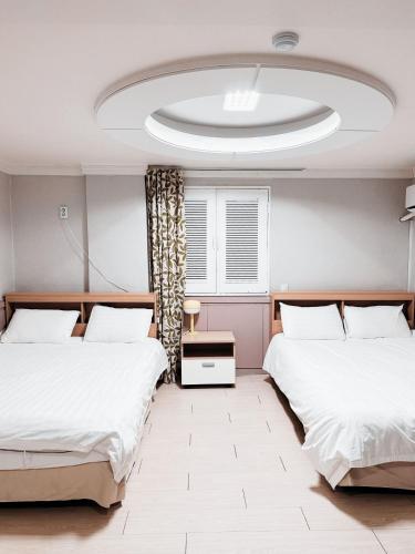 two beds in a bedroom with a large ceiling at Daegu Dongseongro Gyeong`s Hostel in Daegu