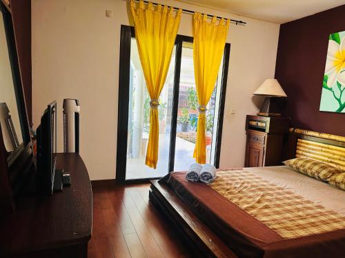 a bedroom with a bed and a window with yellow curtains at Villa F5 vue sur mer 