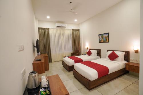 a hotel room with two beds and a television at Hotel Abaam Neil in Kumarakom