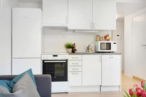 a white kitchen with white cabinets and a microwave at The Apartments Company - Majorstuen in Oslo