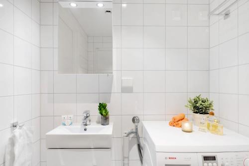a white bathroom with a sink and a mirror at The Apartments Company - Majorstuen in Oslo