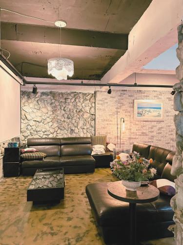 a living room with leather furniture and a stone wall at Daegu Dongseongro Gyeong`s Hostel in Daegu