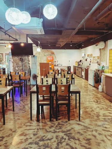 a dining room with tables and chairs and a kitchen at Daegu Dongseongro Gyeong`s Hostel in Daegu