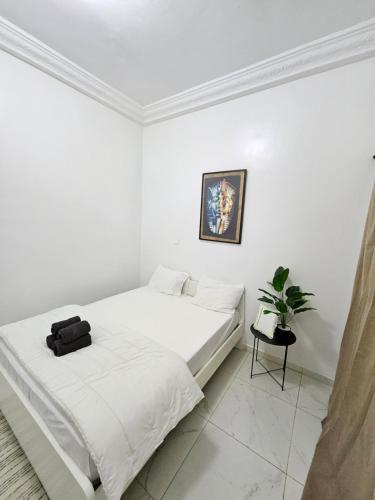 a white bedroom with a bed with a black bag on it at Résidence Jordan in Dakar