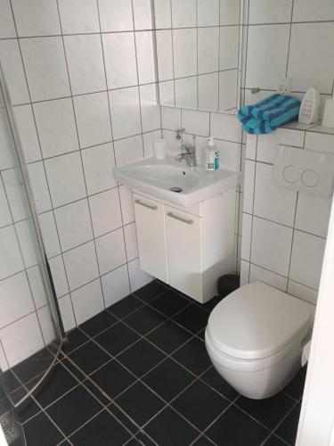 a white bathroom with a toilet and a sink at JR Apartaments in Esbjerg