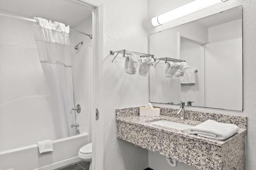 a bathroom with a sink and a mirror and a toilet at Travelodge Suites by Wyndham MacClenny I-10 in Macclenny