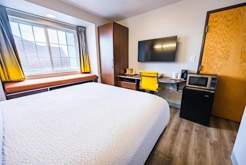 a room with a bed and a desk and a tv at Microtel Inn & Suites Cheyenne in Cheyenne