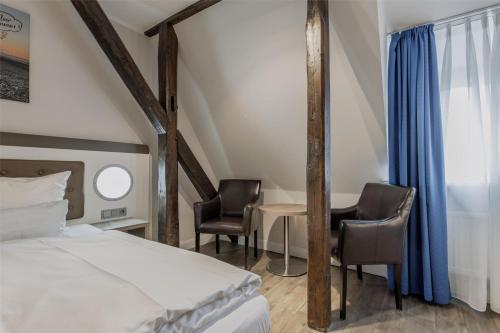 a bedroom with a bed and two chairs and a table at Best Western Plus Theodor Storm Hotel in Husum