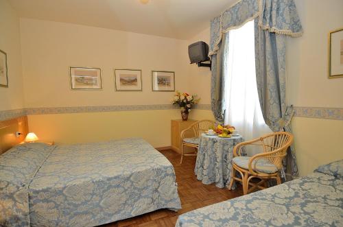 a hotel room with two beds and a table and a window at Villa Angelica in Venice-Lido