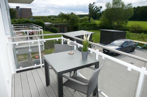 a table and chairs on a balcony with a car at Come In Haffkrug in Haffkrug