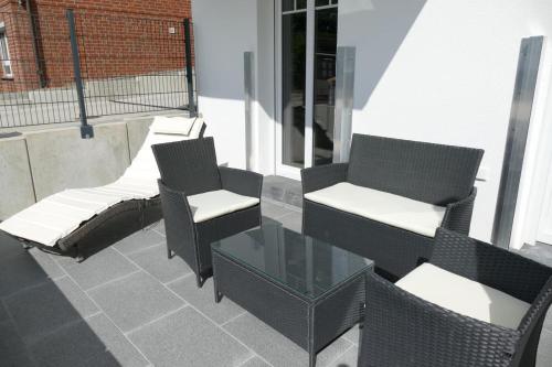 a group of chairs and a glass table on a balcony at Come In Haffkrug in Haffkrug