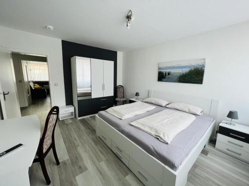 a white bedroom with a bed and a table and a desk at Zur Seeschwalbe in Scharbeutz