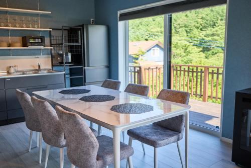 a kitchen with a white table and chairs and a balcony at COCO VILLA 山中湖 -Lake Yamanakako- in Yamanakako