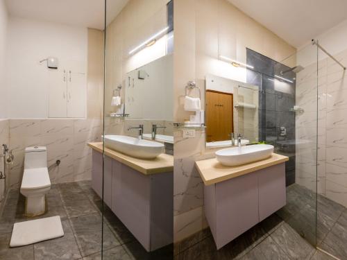 a bathroom with two sinks and a toilet at Aliste Millennium Huda City Centre in Gurgaon
