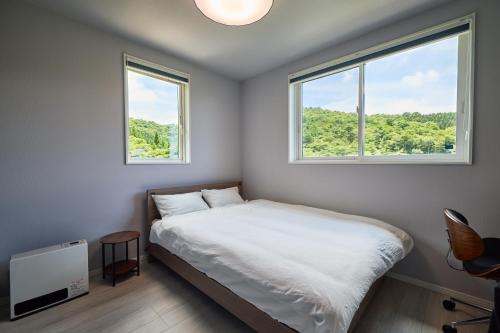 a bedroom with a bed and two windows at COCO VILLA 山中湖 -Lake Yamanakako- in Yamanakako