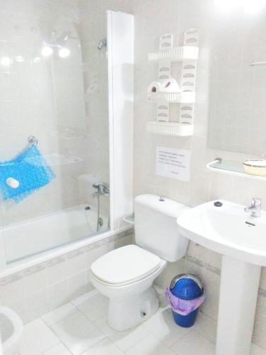 a white bathroom with a toilet and a sink at Dunas y Luz in Rota