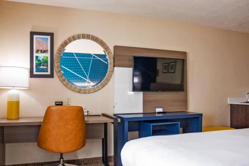 a hotel room with a bed and a desk and a mirror at Comfort Inn & Suites Geneva- West Chicago in Geneva