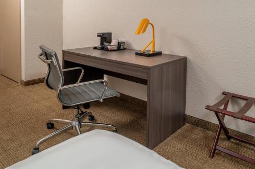 a desk with a chair and a lamp on it at Clarion Pointe Beckley in Beckley