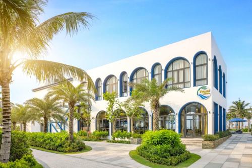 a building with palm trees in front of it at Wyndham Hoi An Royal Beachfront Resort & Villas in Hoi An