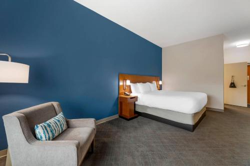 a hotel room with a bed and a chair and a couch at Comfort Inn & Suites Akron South in Akron