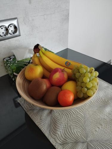 a bowl of fruit on a table with bananas and grapes at Nadi in Plovdiv