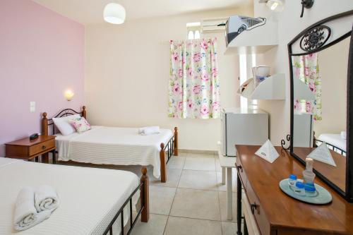 a hotel room with two beds and a desk and a room at Tiniotissa Studios in Tinos