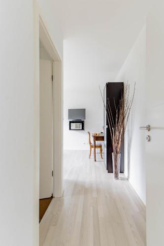 a white hallway with a table and a vase on the floor at Montaney Guests House - EPFL in Ecublens