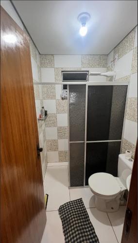 a bathroom with a toilet and a glass shower door at Chácara Bella Vista Mairinque in Mairinque