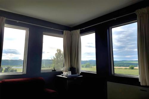 a room with three windows with a view of a field at Ramada by Wyndham Florenceville in Florenceville