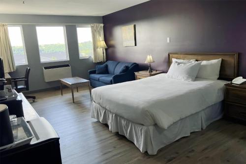 a hotel room with a bed and a blue chair at Ramada by Wyndham Florenceville in Florenceville