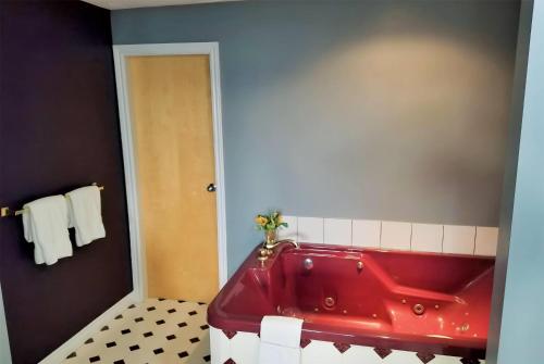 a red tub in a bathroom with a black wall at Ramada by Wyndham Florenceville in Florenceville