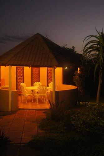 a gazebo with a table and chairs at night at The Fever Tree Guest House in Hluhluwe
